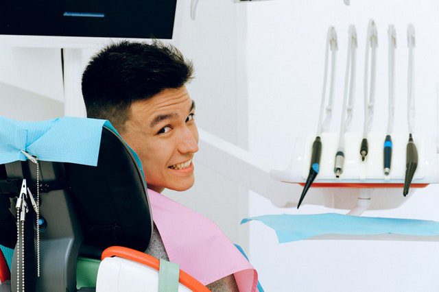 Smiling man seated in a dentist's chair looking backwards over his shoulder.